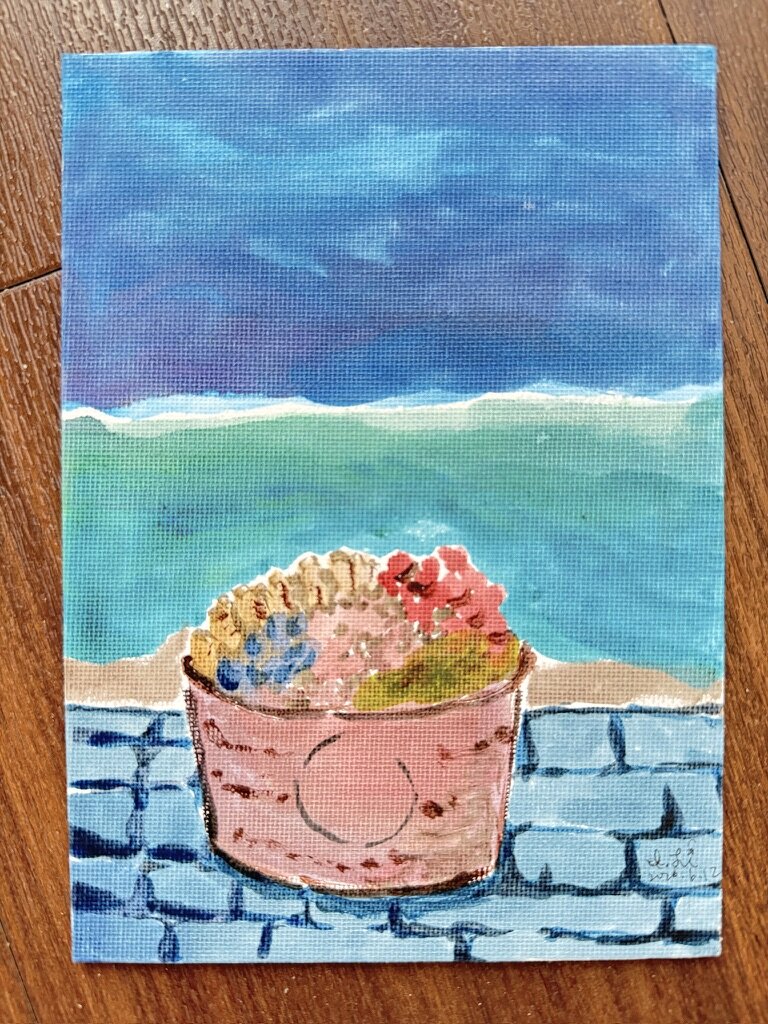 Painting of a flower basket on a wall by the sea.