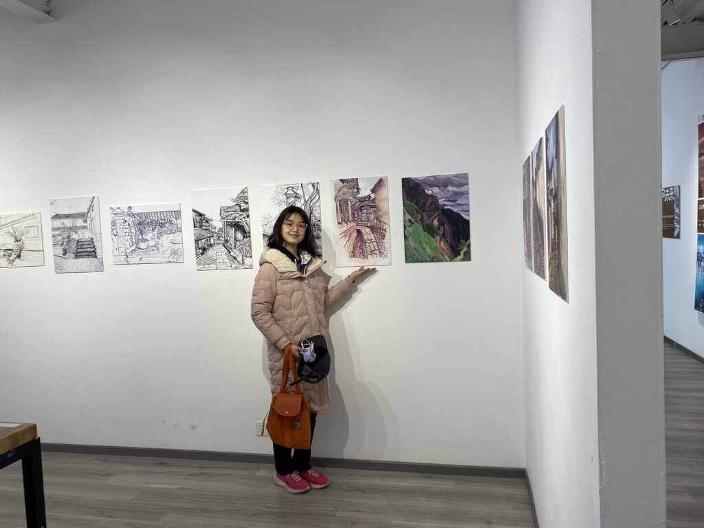 Isabella beside a wall of drawings.
