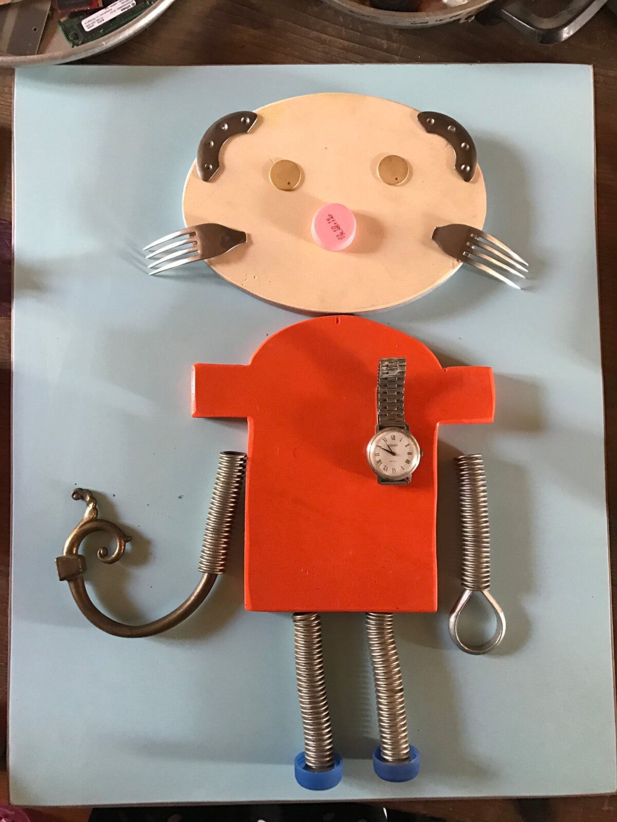 An assemblage figure made from forks, springs, and a watch.